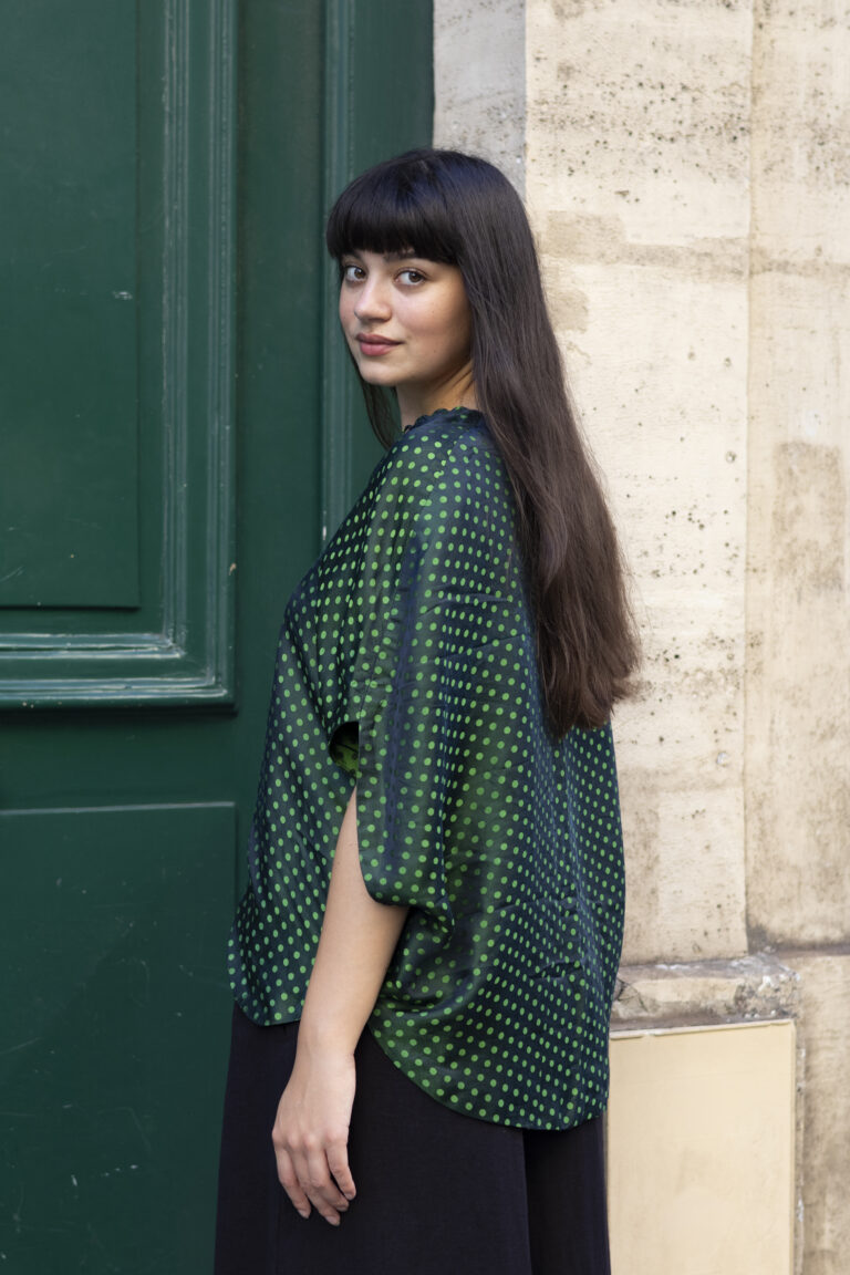 Photo de mode avec une mannequin en tenue verte à petits-pois de 3/4 dos