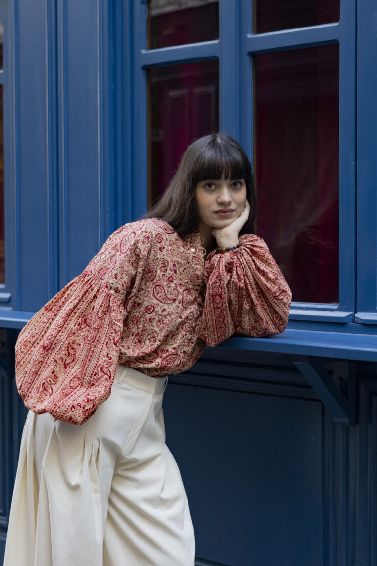 Photo de mode avec une mannequin appuyée sur un rebord de fenêtre portant une chemise à motifs